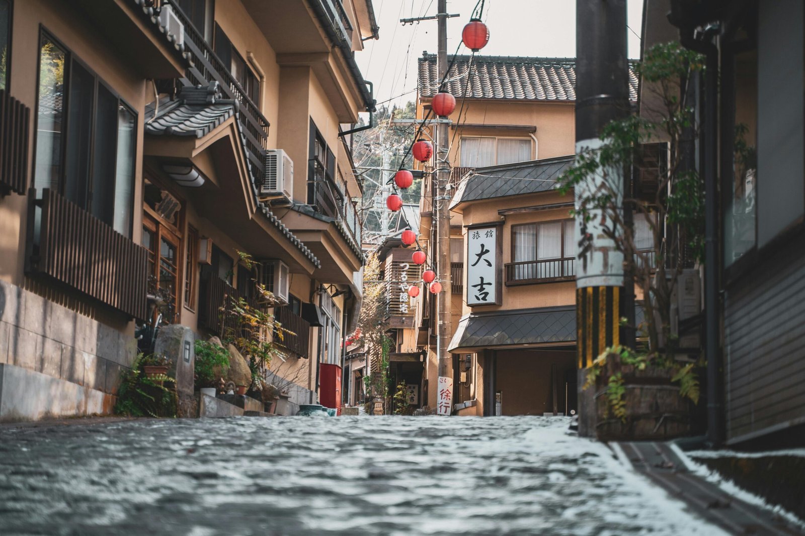 Explore a picturesque street in Osaka with traditional architecture and red lanterns.