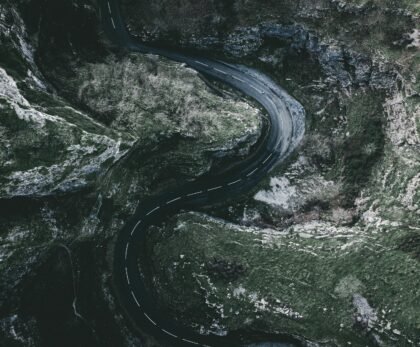 Dramatic aerial shot of a winding road through a gorge in England, showcasing rocky landscapes.