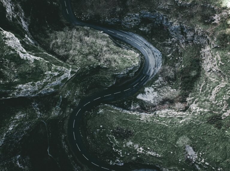 Dramatic aerial shot of a winding road through a gorge in England, showcasing rocky landscapes.